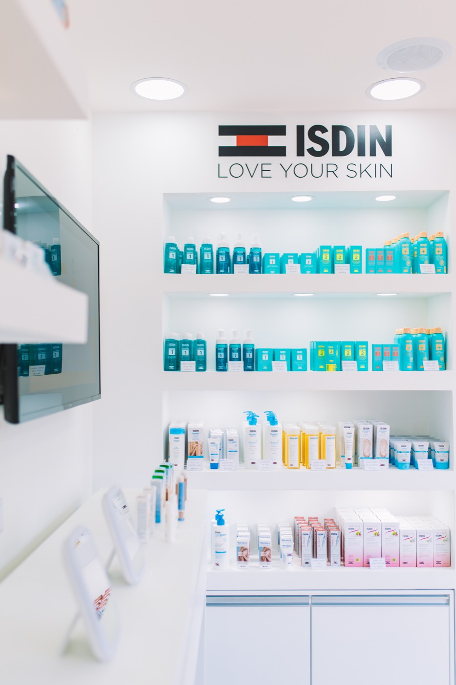 White store interior with lit product shelves and the "ISDIN LOVE YOUR SKIN" logo on the wall