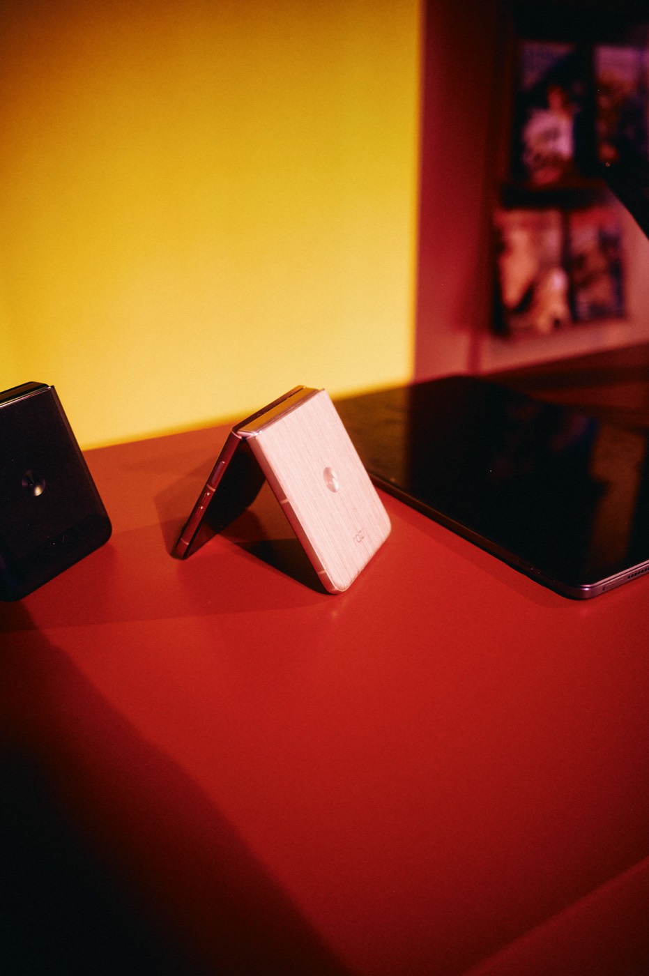 Light-colored foldable phone standing half open on a red counter, with a yellow wall behind